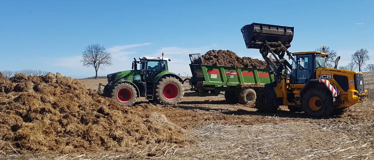 Radlader und mehrere Schlepper mit Streuern auf dem Feld