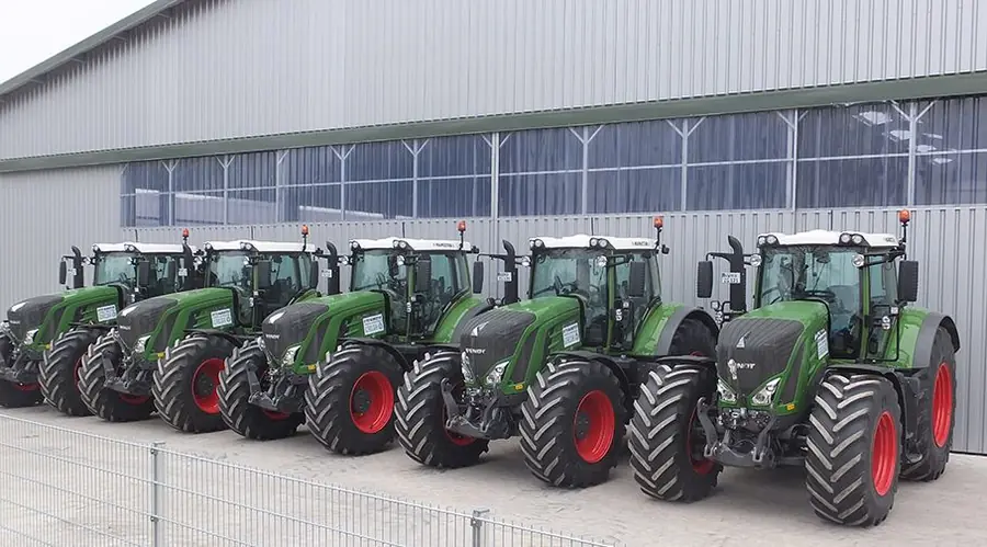 Sechs Fendt-Schlepper stehen in einer Reihe vor der Maschinenhalle