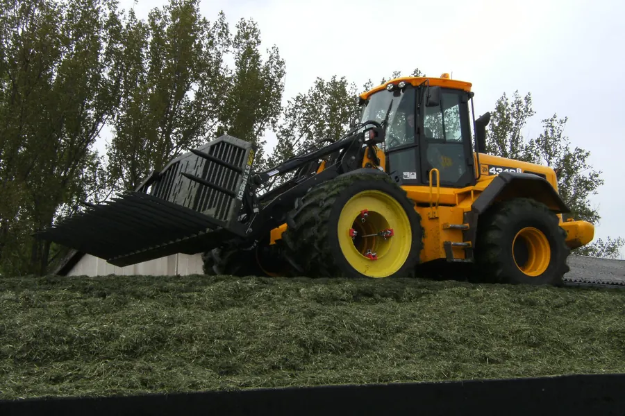 Schlepper mit Schiebeschild verdichtet die Silage im Fahrsilo
