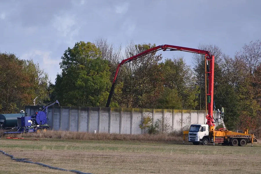 LKW mit ausgefahrenem Kranausleger rührt einen Güllebehälter auf