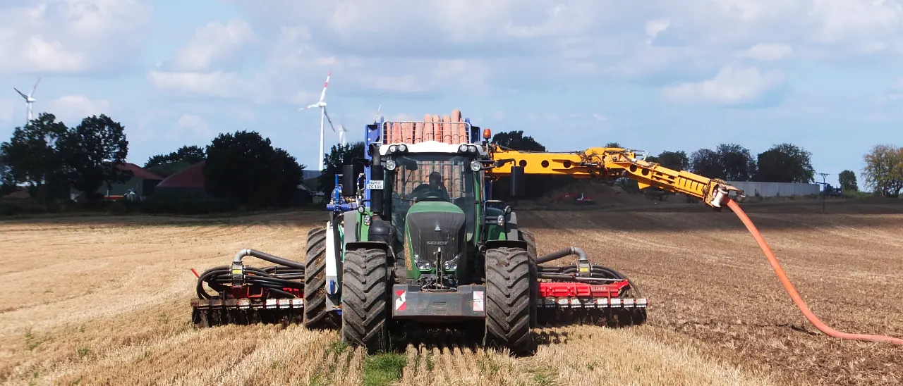 Schlepper mit Scheibenegge und Zubringschlauch auf dem Feld