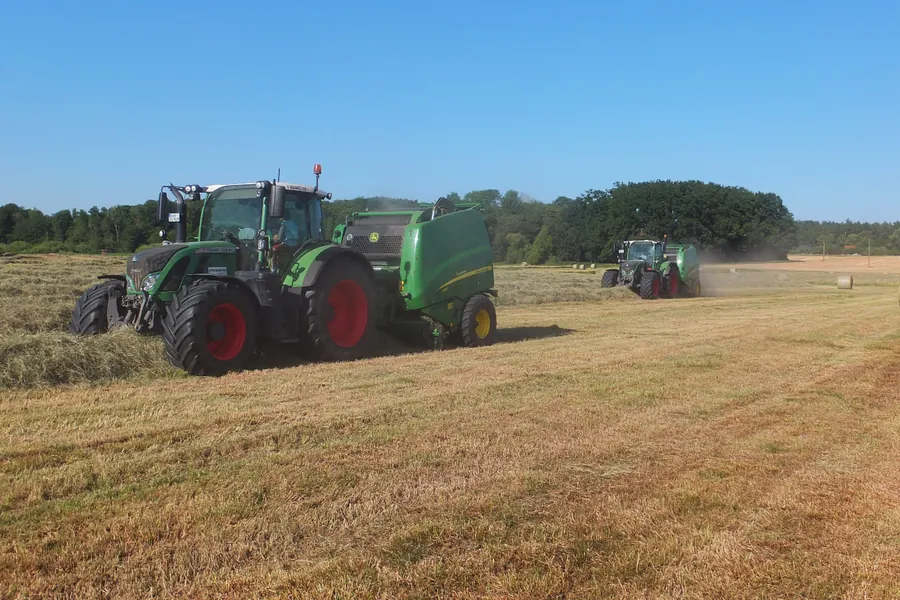 Rundballenpresse und zweites Gespann auf der Grasfläche